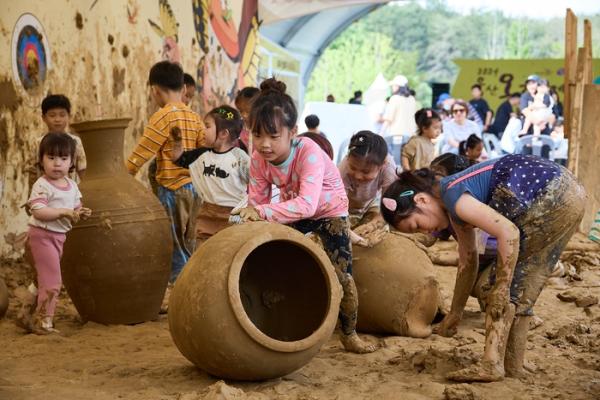 울산옹기축제에 참가한 어린이들이 흙바닥에 옹기를 굴리고 있다. 울주문화재단 제공